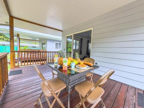 a table and chairs on a deck with a table and fruit at Fare Heana- Beau bungalow Moorea in Moorea