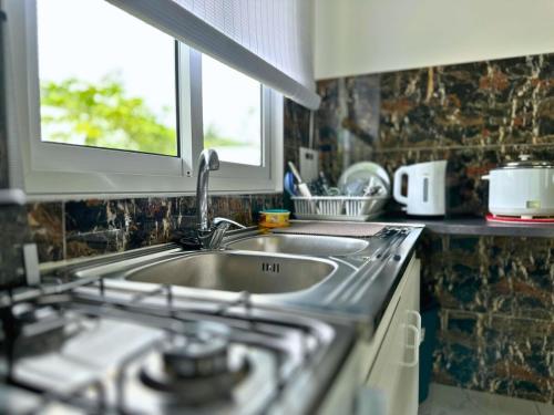 a kitchen with a sink and a stove and a window at Fare Heana- Beau bungalow Moorea in Moorea