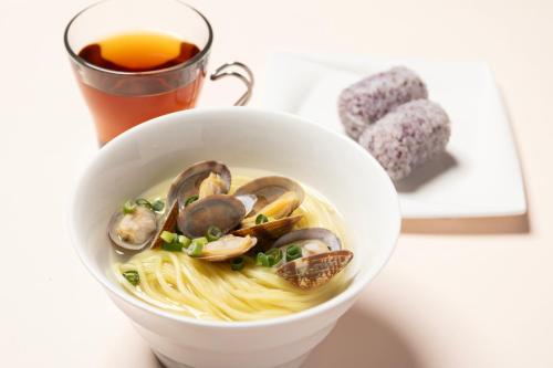 a bowl of noodle soup with mushrooms and a drink at Hotel LOVE JEWEL in Kitakyushu