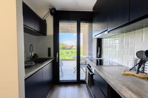 a kitchen with black cabinets and a sliding glass door at Grand Kourouta Pool Apartments in Kourouta
