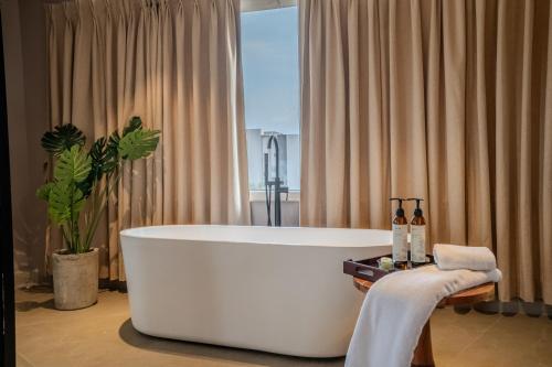 a white bath tub in a bathroom with a plant at Minimalist Panjim in Panaji