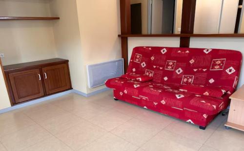- un canapé rouge dans le salon dans l'établissement La pause d'Albepierre, à Albepierre-Bredons