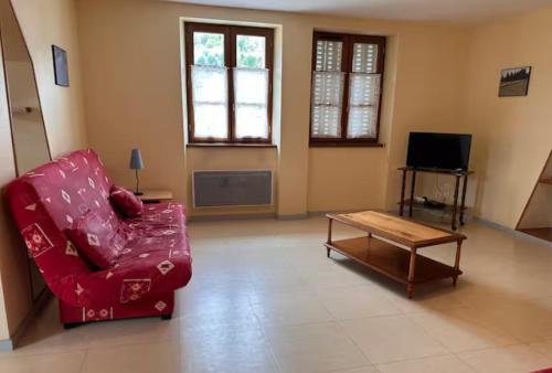 - un salon avec une chaise rouge et une table basse dans l'établissement La pause d'Albepierre, à Albepierre-Bredons