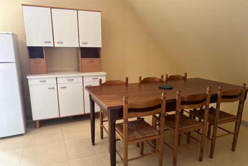 une cuisine avec une table en bois avec des chaises et un réfrigérateur dans l'établissement La pause d'Albepierre, à Albepierre-Bredons