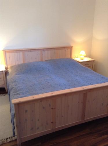 a bedroom with a wooden bed with a blue bedspread at Ferienwohnung Klappacher in Maria Alm am Steinernen Meer