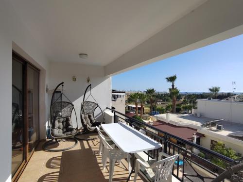 a balcony with a table and chairs and a view at Othello Apartment with Pool, Balcony, Rooftop Hut Tub & 800 m to sandy beach on foot in Paphos City