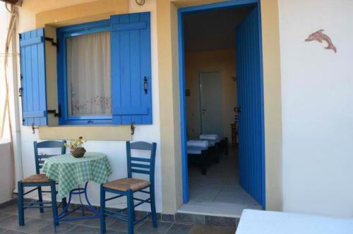 a room with a table and chairs and blue doors at Daira Apartments in Diakofti