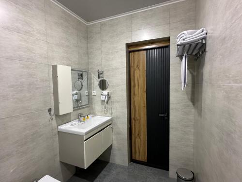a bathroom with a sink and a mirror and a door at Safia Guest House in Andijan