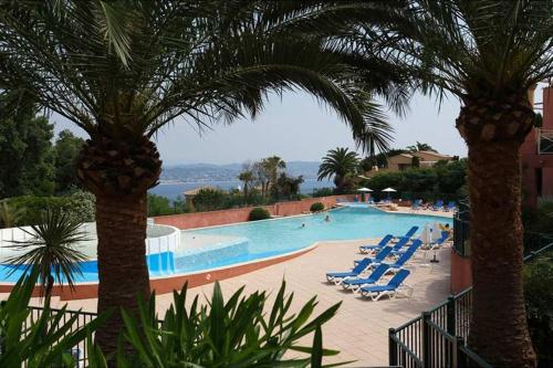 une grande piscine avec des chaises longues et des palmiers dans l'établissement Riviera Azur sea view, swimming pool, jacuzzi, à Théoule-sur-Mer