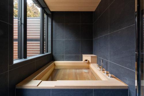 a bath tub in a bathroom with a window at RERESO Motohakone in Hakone
