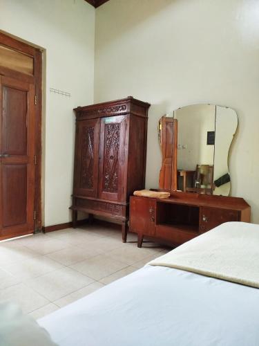 a bedroom with a dresser and a mirror and a bed at Dapur Ethnic Homestay in Bantul