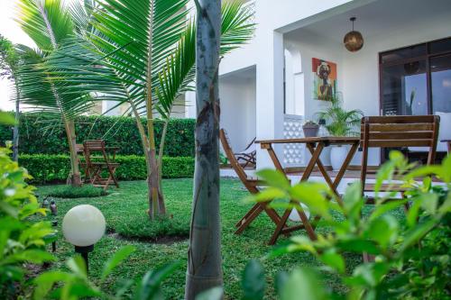 a garden with a table and chairs and palm trees at Hayce Residence Ocean View Apartment in Kilifi