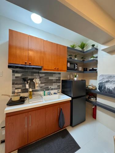 a kitchen with wooden cabinets and a black refrigerator at My Condo City in Lapu Lapu City