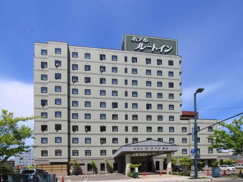 a large white hotel with a sign on top of it at Hotel Route-Inn Obihiro Ekimae in Obihiro