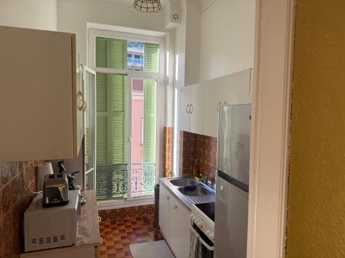 une cuisine avec évier et une fenêtre avec volets verts dans l'établissement Appartement 3 pièces 5 min plage, à Beaulieu-sur-Mer