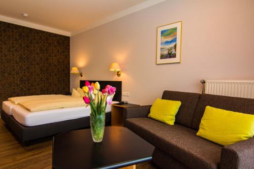 a hotel room with a bed and a vase of flowers on a table at Garni Hotel & Ferienwohnungen Seeschlößchen in Waldeck