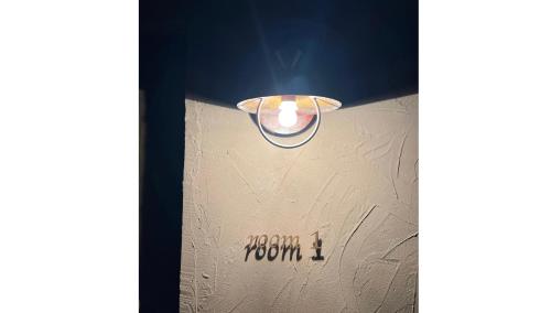 a light hanging from a wall with the word room on it at 宮古島の自然豊かで静かなエリアroom1オリジナルインテリア小物が溢れる空間 in Miyako Island