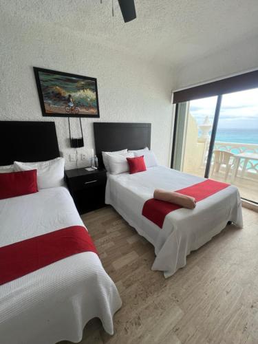 two beds in a hotel room with a view of the ocean at Cancun plaza frente al mar in Cancún