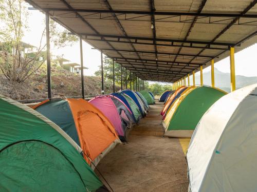 a row of tents are lined up under a building at The Hosteller Bhandardara in Bhandardara 