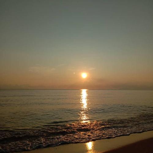 a sunset on the beach with the sun setting at LR homestay in Kampong Ru Sepuloh