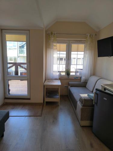 a living room with a couch and two windows at Apartamenty Turkusowe in Rowy