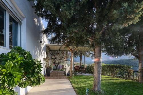 a porch of a house with a tree at MariAndry Villa, Secluded Retreat with Pool, BBQ & HotTub, By ThinkVilla in Episkopí- Rethimno