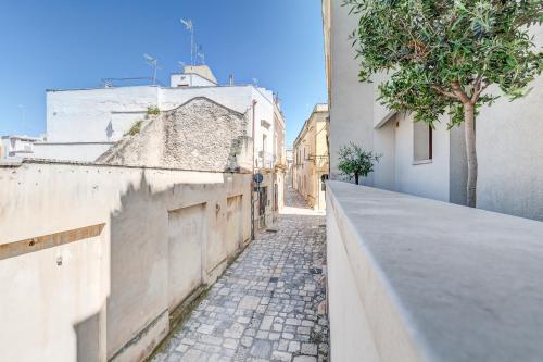an alley in a city with buildings and a tree at Santo Stefano Raro Rooms Collection in Brindisi