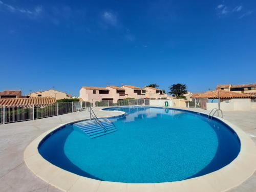 une grande piscine bleue avec une chaise dans une cour dans l'établissement Appartement Résidence Aphrodite Village naturiste à Port Leucate, à Leucate-Plage