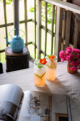 a book and two drinks on a table with flowers at Treehouse escape in Kværndrup