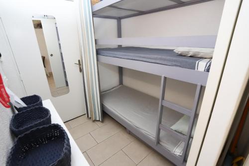 Cette petite chambre comprend des lits superposés et un miroir. dans l'établissement St cyprien appartement avec piscine, à Saint Cyprien Plage