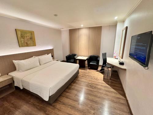 a hotel room with a bed and a desk and a television at Orchardz Hotel Industri Jakarta Kemayoran in Jakarta