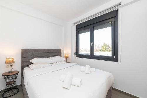 a white bedroom with two beds and a window at Olympiada Residential Complex & Villas in Ofrínion