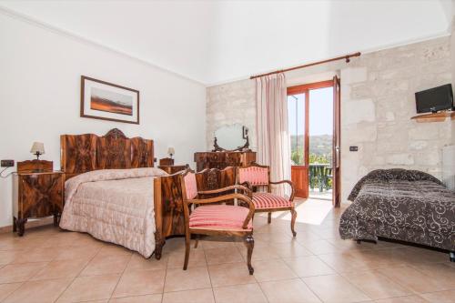 a bedroom with a bed and chairs and a television at B&B Il Giardino Dei Mandarini in Modica
