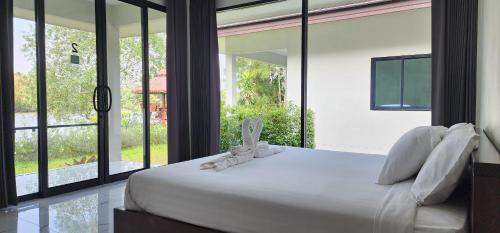 a bedroom with a large white bed with large windows at Suan Son Villa Koh Sa Nher สวนสนธิ์วิลล่า เกาะเสนอ SHA in Surat Thani