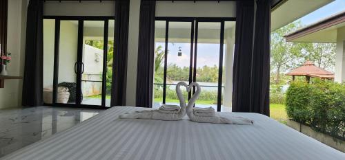 a white bed with two towels on top of it at Suan Son Villa Koh Sa Nher สวนสนธิ์วิลล่า เกาะเสนอ SHA in Surat Thani