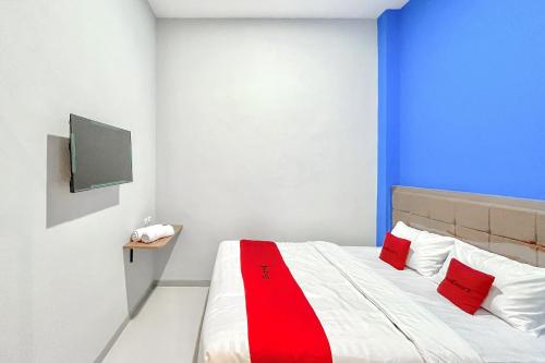 a bedroom with a bed with red and white pillows at RedDoorz Syariah near Majapahit Semarang in Alastuwo