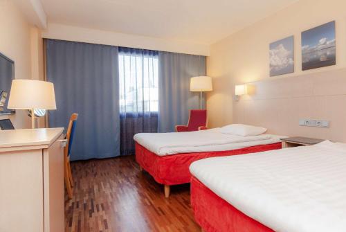 a hotel room with two beds and a red chair at Scandic Mikkeli in Mikkeli