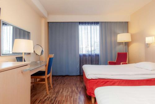 a hotel room with two beds and a desk at Scandic Mikkeli in Mikkeli
