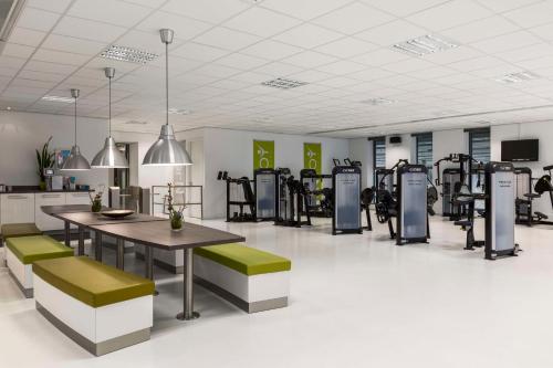 a fitness room with tables and benches and machines at NH Den Haag in The Hague