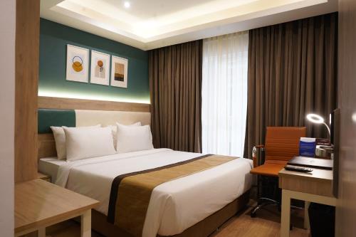a hotel room with a large bed and a desk at Sarovar Portico Kolkata in Kolkata