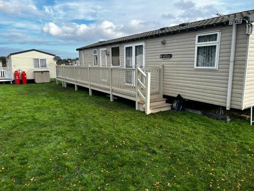 a mobile home with a porch and a yard at Serenity 1 and Serenity 2 Central lounge 3 bedrooms sleep 6 with 2 bathrooms in Lowestoft
