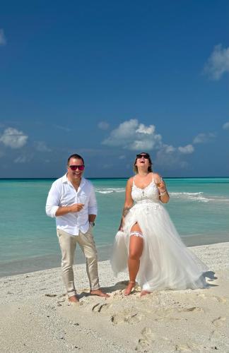 a bride and groom standing on the beach at Three Hearts Guesthouse and Villas in Fulhadhoo