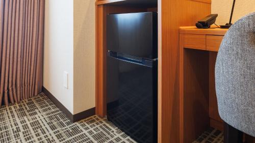 a black refrigerator in a room with a desk at JR-East Hotel Mets Komagome in Tokyo
