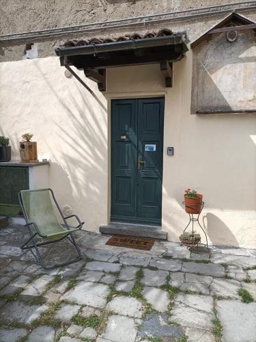 a green door on a white house with a chair at Il CORTILETTO in Acquaseria