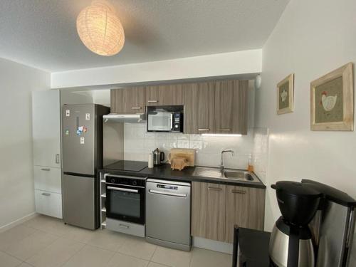 une cuisine avec un réfrigérateur en acier inoxydable et un évier dans l'établissement Appartement cosy proche centre Capbreton, situé dans un cadre boisé, à Capbreton