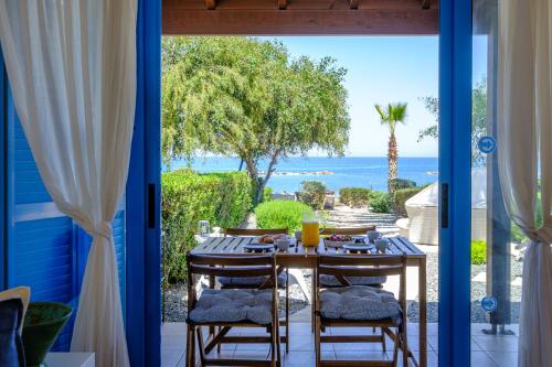 a table and chairs on a patio with a view of the ocean at Aura Beachfront Residence by Nomads in Polis Chrysochous