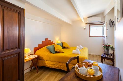 a small bedroom with a yellow bed and a table at Le Fangassier in Saintes-Maries-de-la-Mer