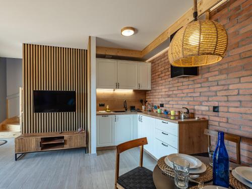 a kitchen with white cabinets and a brick wall at Pod Lasem Apartamenty in Łukęcin