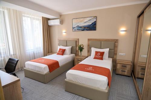 a hotel room with two beds and a desk at Crown Hotel in Bishkek