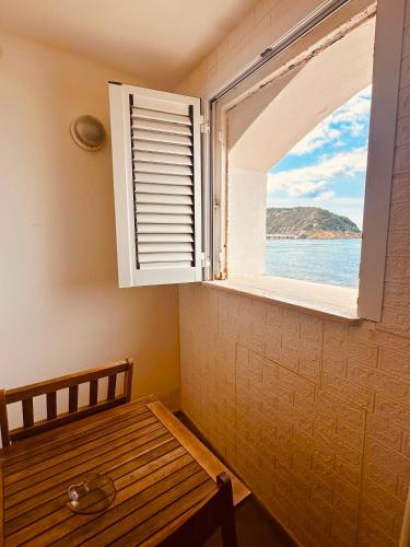 a window in a room with a wooden table and a bench at Lido Di Procida Guest House in Procida